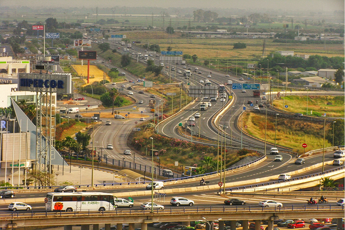 La desasosegante sensaci&oacute;n de desorden de las infraestructuras de movilidad en la aglomeraci&oacute;n urbana de Sevilla
Las infraestructuras del transporte (junto con las de telecomunicaciones), facilitan la movilidad de personas, mercanc&iacute;as, capitales e informaci&oacute;n. Las redes de autov&iacute;as y otras v&iacute;as r&aacute;pidas act&uacute;an como un gran sistema circulatorio, de forma semejante a como lo hace el flujo sangu&iacute;neo por las venas de un ser vivo. Por ello, las aglomeraciones urbanas se asemejan con frecuencia a un gran organismo, con sus funciones fisiol&oacute;gicas y sus trastornos propios. Estas infraestructuras no solo transforman f&iacute;sicamente el espacio, al conectar unos territorios a costa de fracturar otros, creando siempre nuevos paisajes. Tambi&eacute;n alteran la forma de experimentar el espacio y el tiempo. Estas v&iacute;as r&aacute;pidas multiplican nuestra presencia en la ciudad, y nos permiten vivir muchos &ldquo;momentos&rdquo; y presenciar muchos &ldquo;lugares&rdquo; a lo largo del d&iacute;a. Esta reducci&oacute;n del espacio y la consiguiente aceleraci&oacute;n del tiempo es un atributo esencial de la condici&oacute;n posmoderna, de la que tanto participa la ciudad posindustrial.&nbsp;